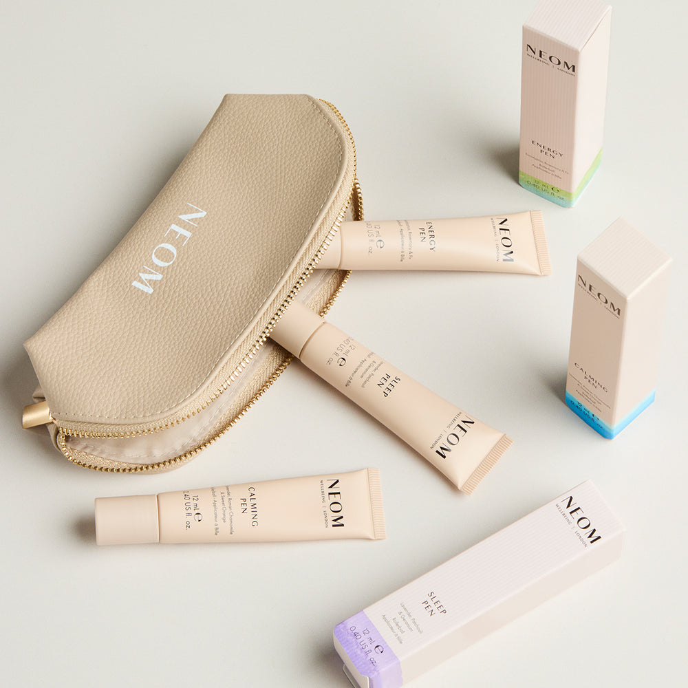 NEOM pens including a gold pouch and pens on a light background