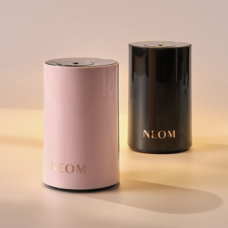 Two NEOM products, one pink and one black, on a beige background