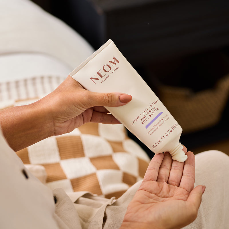 A person putting the NEOM perfect nights sleep magnesium body butter onto their hands