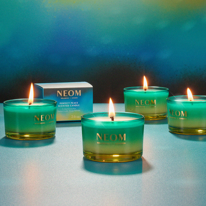 NEOM candles with a blue gradient on a reflective surface and blue background