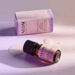 NEOM Perfect Night’s Sleep essential oil blend bottle lying beside its box with oil droplets on the surface.