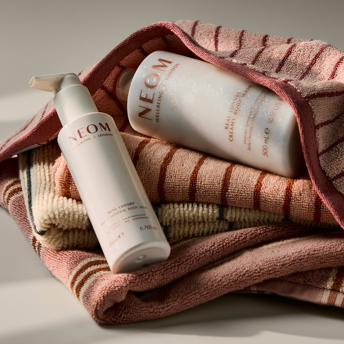 NEOM real luxury multi-mineral body milk and creamy body wash wrapped in a towel