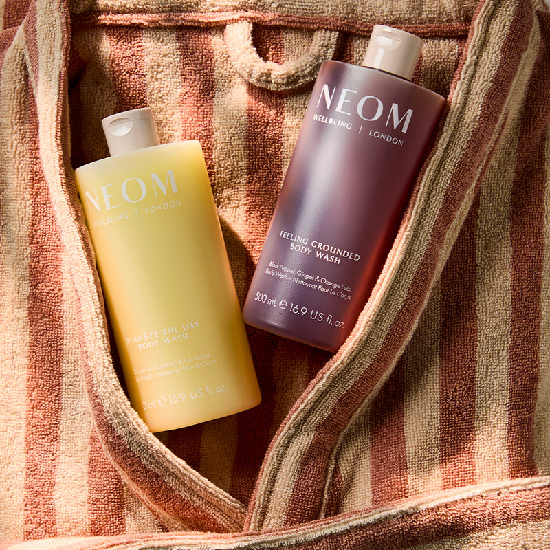 NEOM squeeze the day and feeling grounded body washes layed flat on a towel