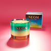 NEOM scented candle with a box on a pink background