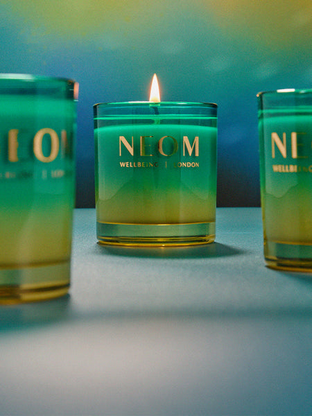 NEOM Perfect Peace candle with a gradient design on a blue background