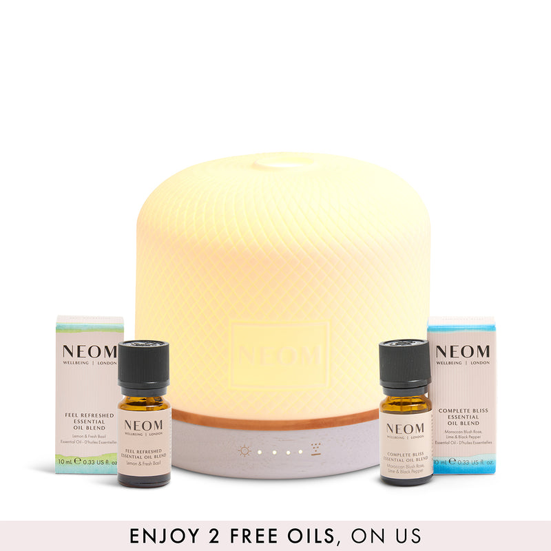 NEOM pod luxe diffuser with 2 essential oil blends with a banner saying '2 free oils, on us' on a white background
