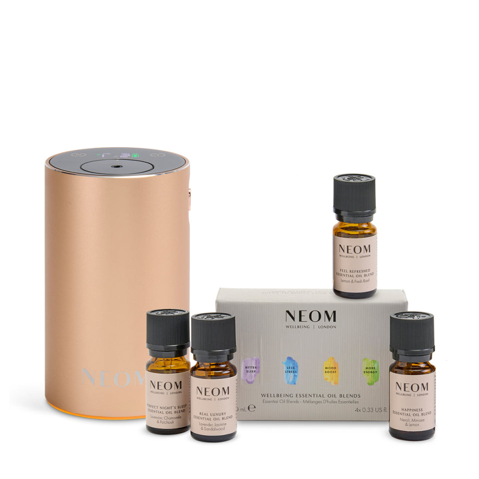 NEOM Pod MIni+ in rose gold with wellbeing essential oil blend collection on a white background