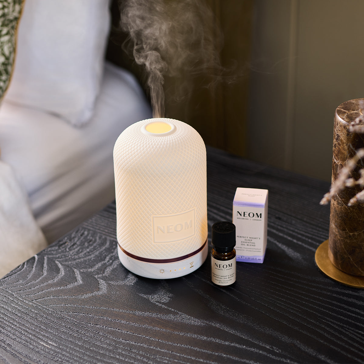 NEOM wellbeing pod and perfect nights sleep essential oil on a bedside table
