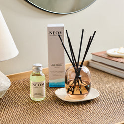 NEOM real luxury reed diffuser and box on a weaved table