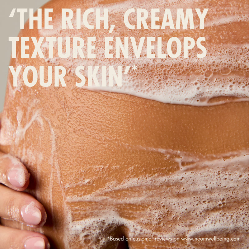 “Close-up of a person’s shoulder covered in soapy lather with a hand resting on the skin. Large text reads: ‘The rich, creamy texture envelops your skin.’ Small print: ‘*Based on customer reviews on www.neomwellbeing.com.’”