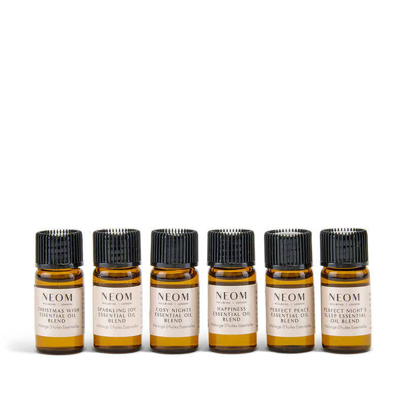 Set of six NEOM Christmas essential oil bottles on a white background