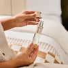 A person holding NEOM perfect night's sleep mist in a bedroom