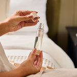 A person holding NEOM perfect night's sleep mist in a bedroom