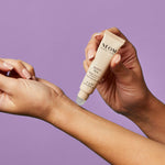 Person applying NEOM Sleep Pen to their wrist against a purple background