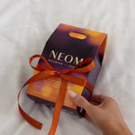 NEOM Sleep Saviours Perfect Night’s Sleep gift set with orange ribbon on white bedding.