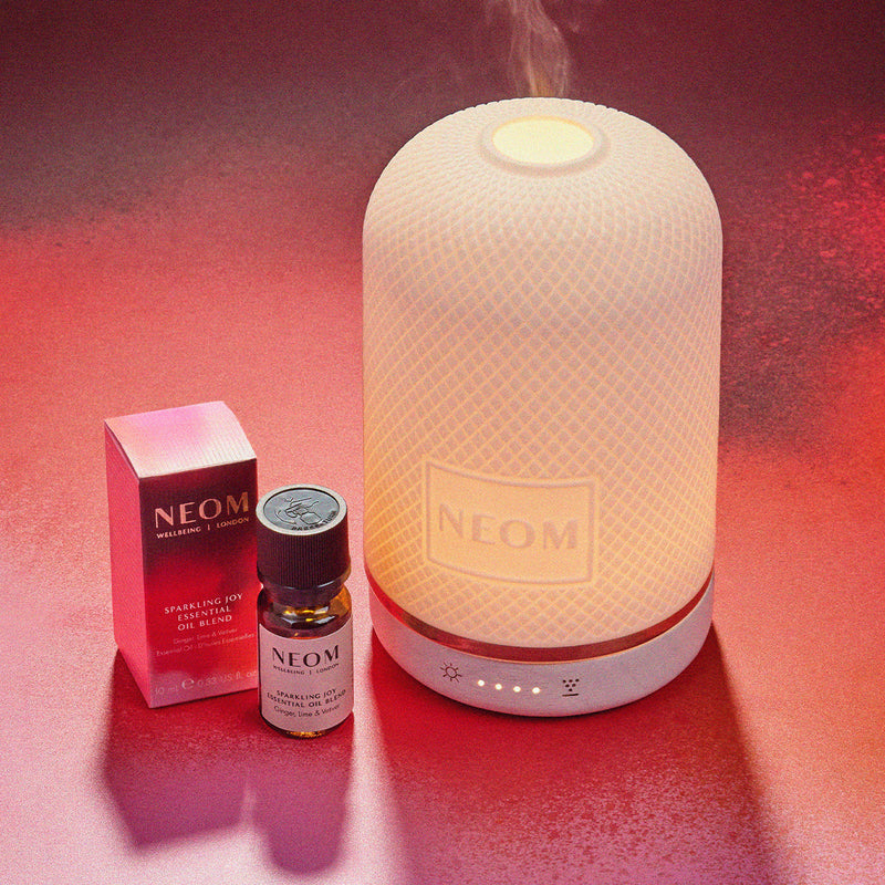 Neom diffuser and essential oils on a red background