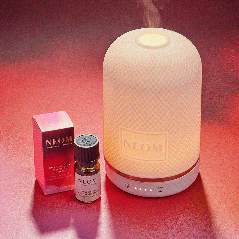 NEOM diffuser and essential oil bottle on a red background