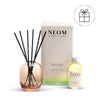 NEOM diffuser set with reeds and bottle on a white background with a Perfect Gift Roundel with a present