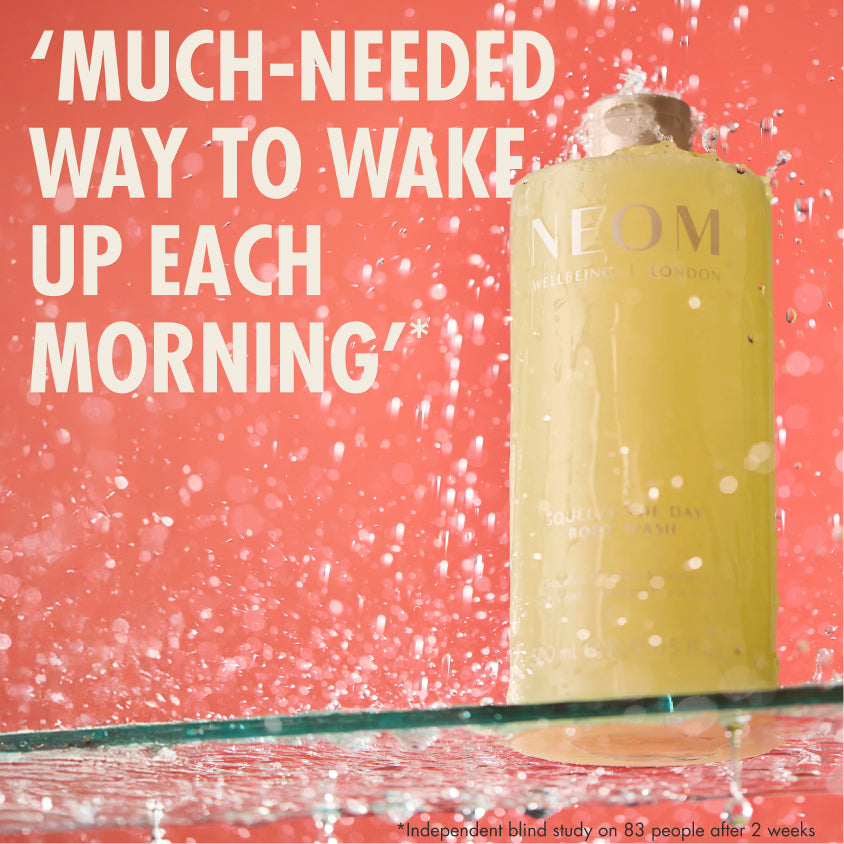 “NEOM Squeeze the Day Body Wash bottle on a pink background with water splashes. Large text reads: ‘Much-needed way to wake up each morning.’ Small print: ‘*Independent blind study on 83 people after 2 weeks.’”