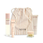 NEOM product set with a beige striped drawstring bag on a white background
