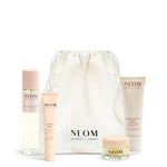 NEOM Sweet Dreams Travel Kit  including a pillow mist, sleep pen, wonder balm and body butter with a white drawstring bag on a white background.