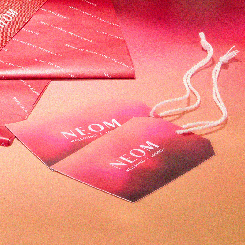 NEOM branded product packaging on a gradient background