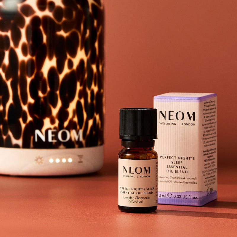 NEOM essential oil blend bottle and packaging on a red background