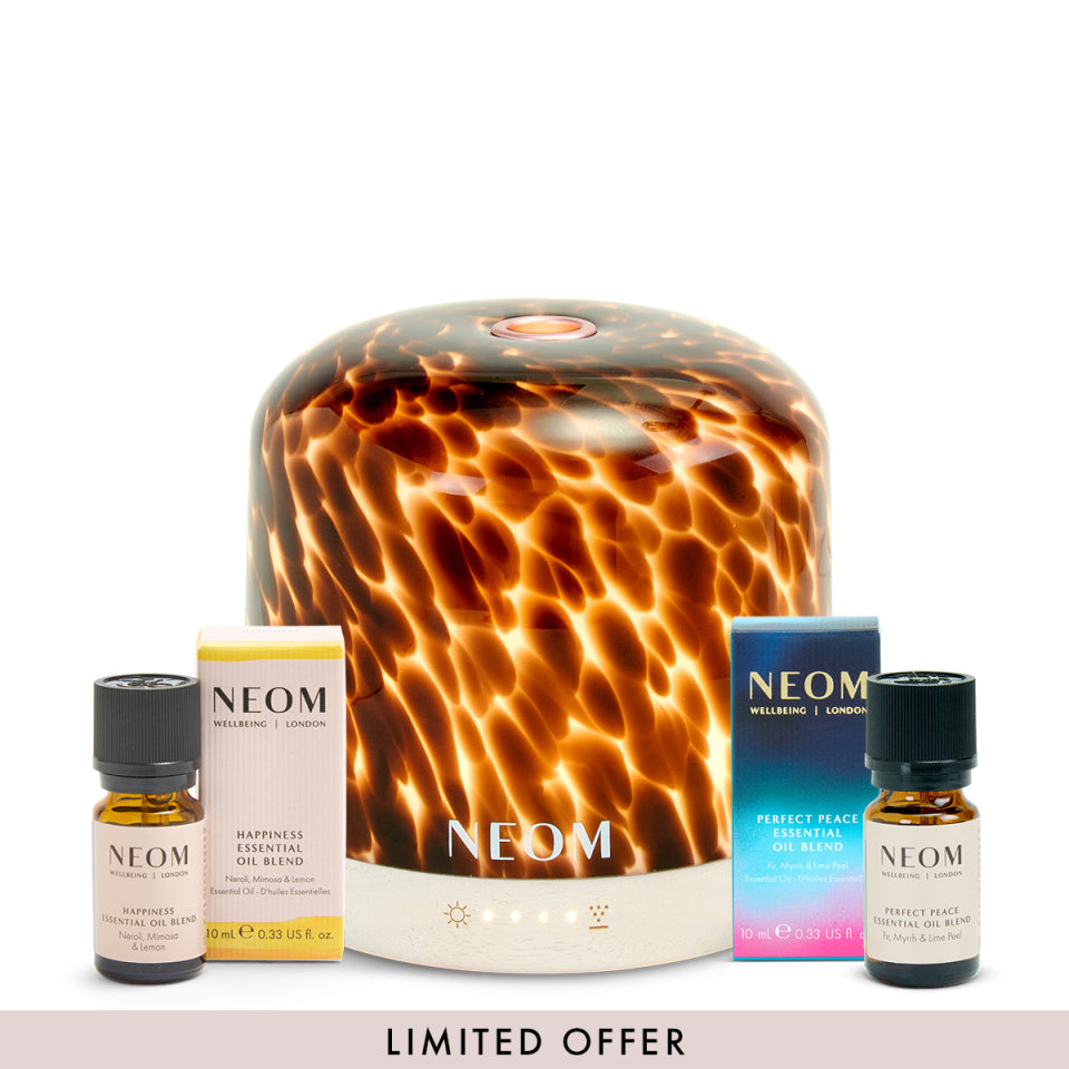 NEOM tortoiseshell pod luxe diffuser and happiness essential oil blend and perfect peace essential oil blend with packaging on a white background