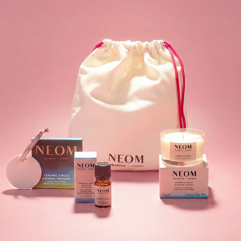 NEOM products and a drawstring bag on a pink background