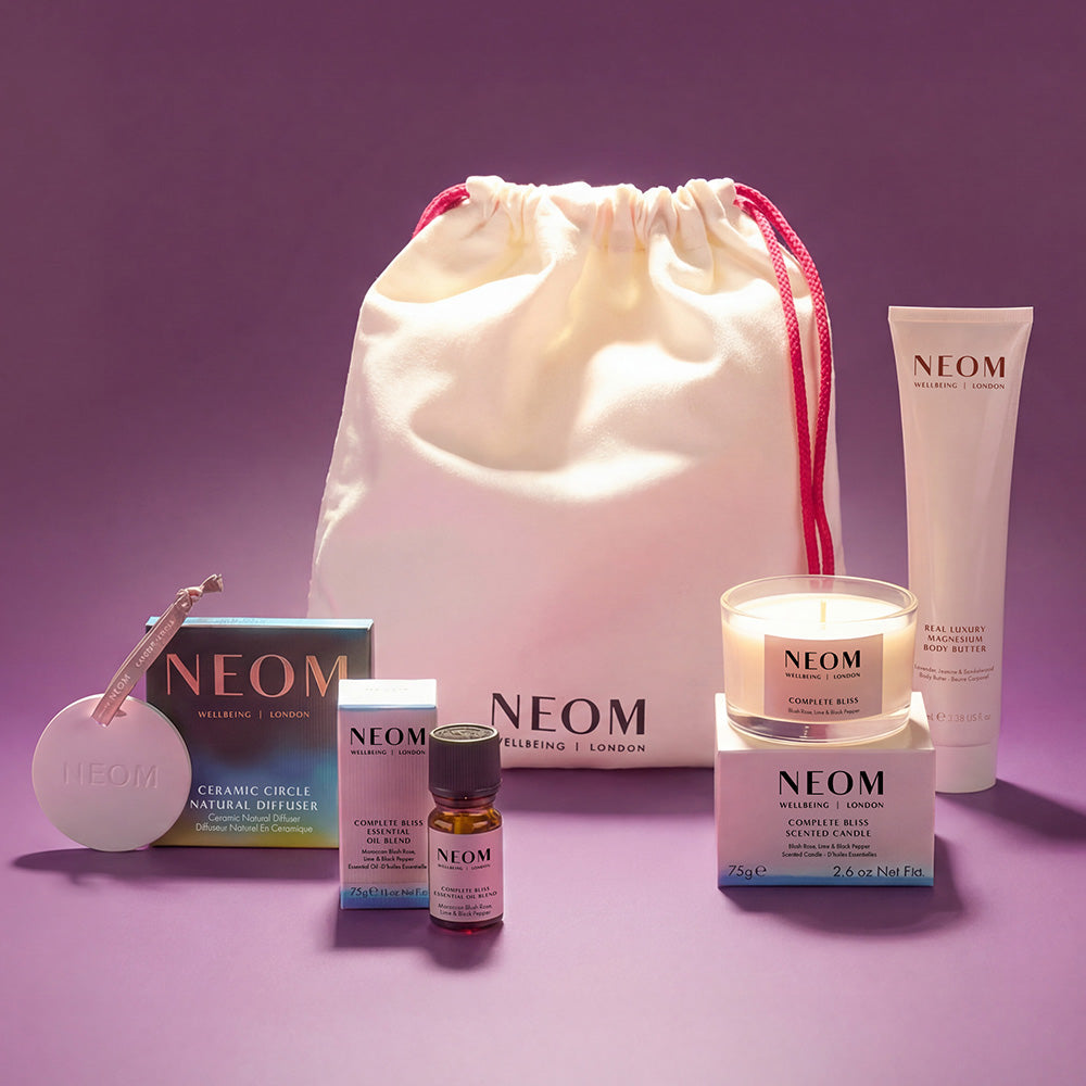 NEOM products with a drawstring bag on a purple background