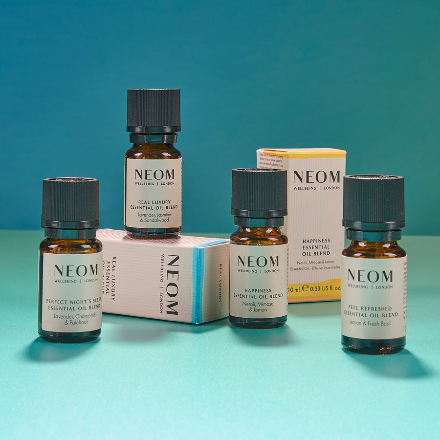 NEOM essential oil bottles and packaging on a teal background