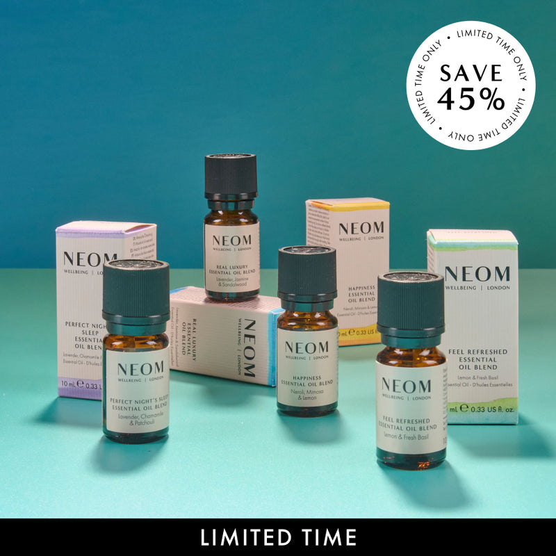 NEOM essential oil bottles and packaging on a teal background