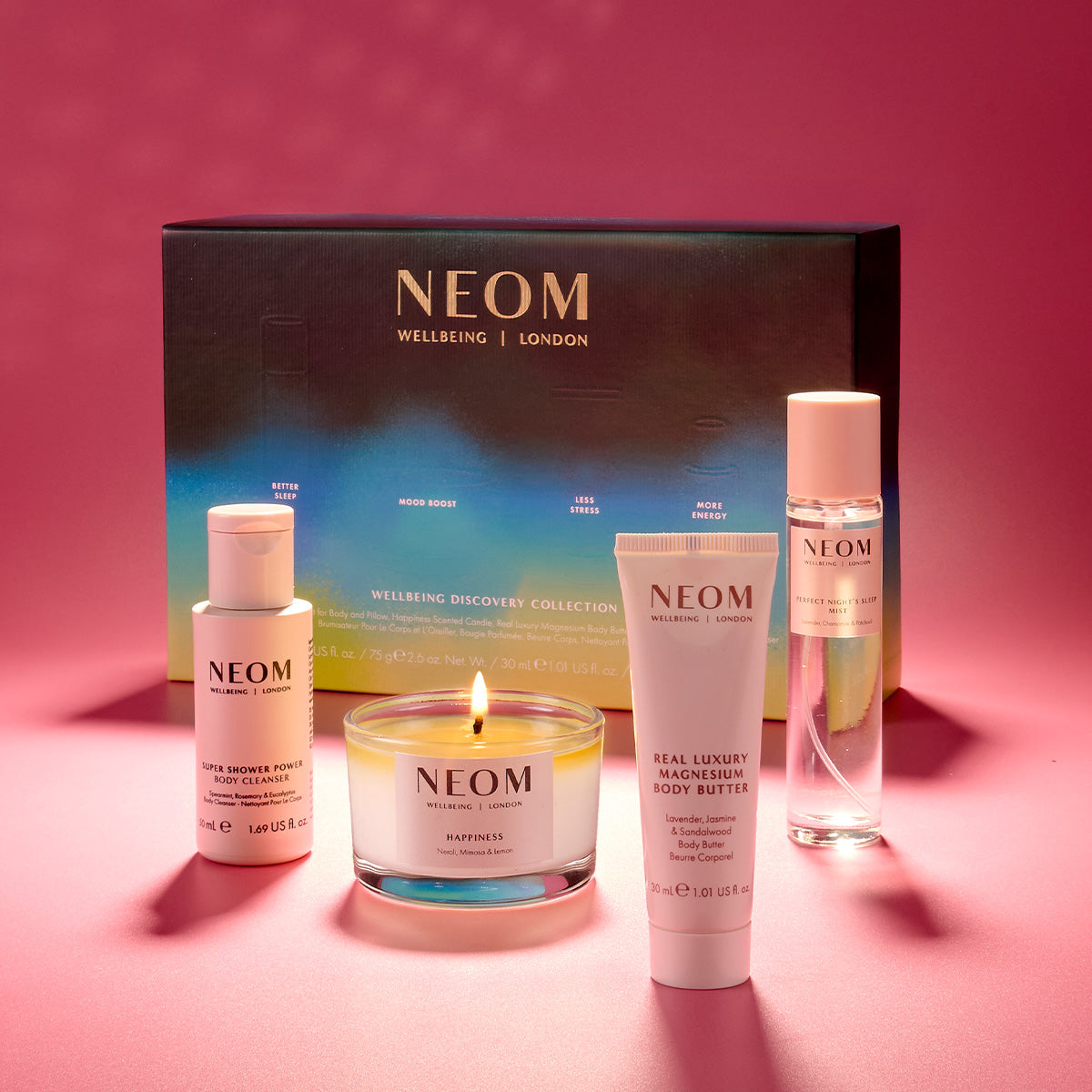 NEOM skincare products including bottles, a candle, and a tube on a pink background