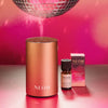 NEOM diffuser and essential oil blend on a reflective surface with a pink background