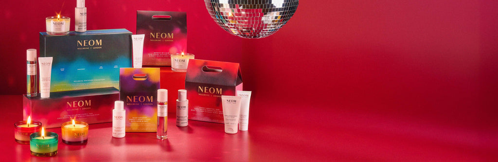 NEOM gift set products and candles on a red background