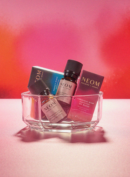 NEOM Christmas essential oils with gradient colours on a red background