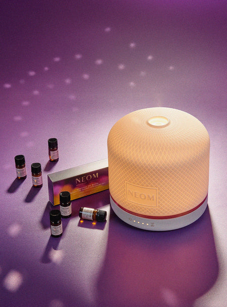 NEOM Electric Pod Luxe Diffuser with Christmas essential oils with gradient colours on a purple background