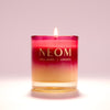 NEOM candle with a gradient colour design on a light pink background