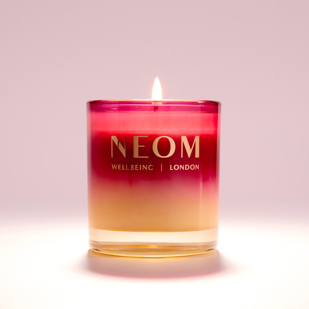 NEOM candle with a gradient colour design on a light pink background