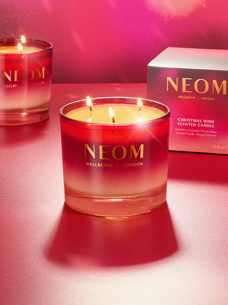 Neom scented Christmas Wish candle with a box in the background on a red surface